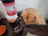 a small statue of a woman holding a fan next to other items on a table