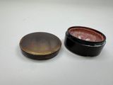 a small black box with a red lid and a brown lid