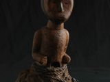 une figurine en bois posée sur un morceau de bois