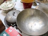 un grand saladier en métal posé sur une table, à côté d'autres objets
