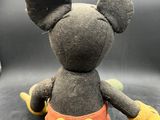 mickey mouse plush toy sitting on a black surface with a black background