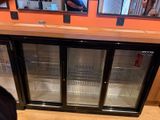 un homme debout devant une vitrine à trois portes en verre