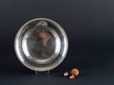 a silver plate with nuts in it on a black background