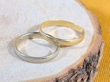 two wedding rings sitting on top of a piece of wood