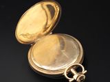 a gold pocket watch on a black surface