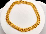 gold plated chain bracelet on a white plate with a black background