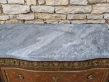 a marble top chest of drawers in front of a brick wall
