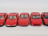 six red model cars are lined up in a row on a white surface