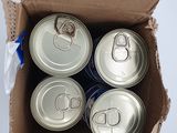 six canettes de soda dans une boîte en carton posée sur une surface blanche