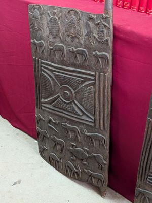 une paire de panneaux de porte anciens en bois sculpté posés sur une table recouverte d'une nappe rouge