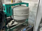 une bétonnière posée dans une pièce, avec une échelle à côté