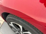 a close up of a red car ' s tire on the street