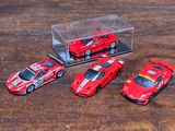 quatre petites voitures rouges dans une vitrine posée sur une table en bois