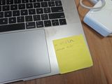 a laptop with a sticky note attached to the keyboard