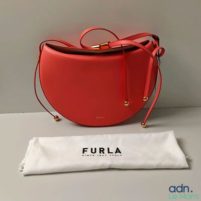 Le sac à main rouge est posé sur la table, à côté d'un sac blanc.
