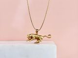 un collier représentant un lion en or posé sur un bloc de marbre, sur fond rose