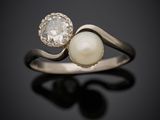 une bague en perles blanches et diamants sur une surface noire