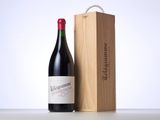 the bottle of red wine is next to a wooden box