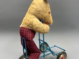 un ours en peluche assis sur un petit vélo jouet