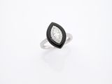 une photo d'une bague en diamant en noir et blanc posée sur une surface blanche