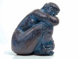 a statue of a man sitting on a white surface