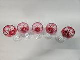 six wine glasses are lined up in a row on a white surface