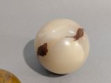 a white ball with brown spots on it next to a wooden ball