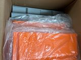 a person holding a box full of orange shirts