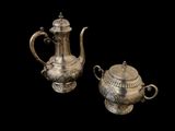pair of antique silver teapots on black background with black background