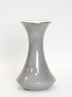 a gray vase with a gold rim sitting on a white surface
