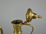 a brass tea pot with a brass handle on a table