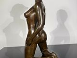 statue of a woman sitting on a black surface with a shadow on the wall