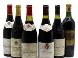 six bottles of wine are lined up in a row on a white surface