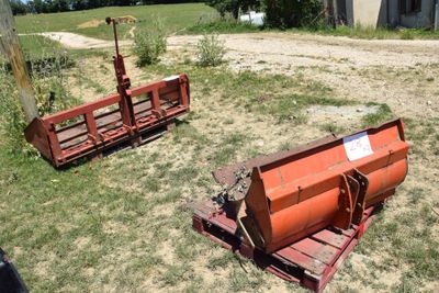 two farm equipment that are sitting in the grass