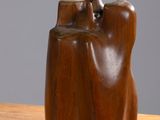a wooden sculpture on a table with a gray background