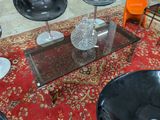 une table basse en verre avec des chaises noires et un vase posé dessus