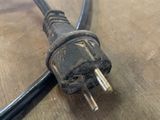 a black cord connected to an electrical plug on a wooden table