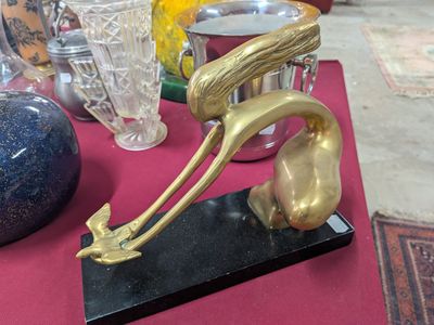 une statue en or représentant un oiseau, posée sur un socle noir