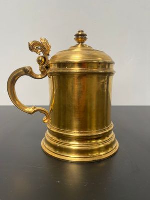 an antique brass coffee pot with a dragon handle on a black table