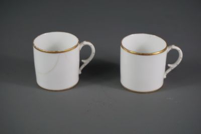deux tasses blanches aux bords dorés sont posées sur une surface grise