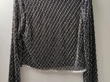 un pull noir et blanc accroché au mur à côté d'un cintre