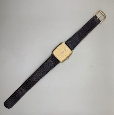 gros plan d'une montre sur une surface blanche avec un bracelet noir