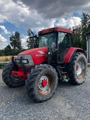 an image of a red tractor parked in a gravel lot