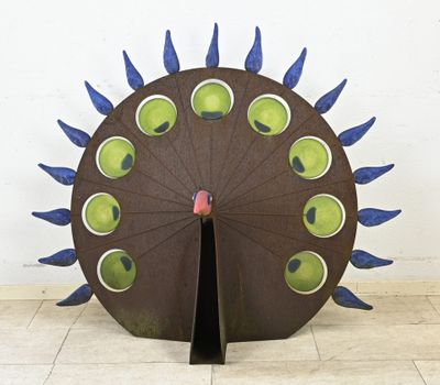 une sculpture de paon en papier, avec des yeux verts