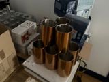 a table with a bunch of copper cups on top of it