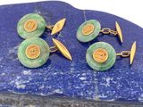 trois paires de boutons de manchette verts et dorés posés sur une dalle de pierre bleue