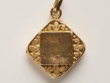 a close up of a gold pendant on a white surface
