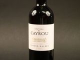 the bottle of red wine is sitting on a black surface