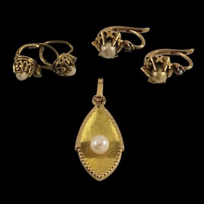 trois bagues en or et un pendentif en perle sur fond noir