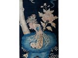 an image of a blue and white rug with a vase of flowers on it